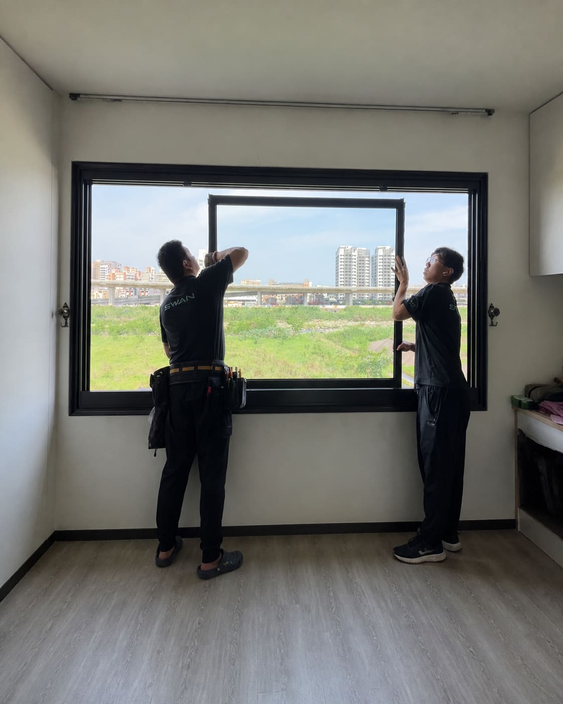 兩位施工人員共同安裝大型窗扇